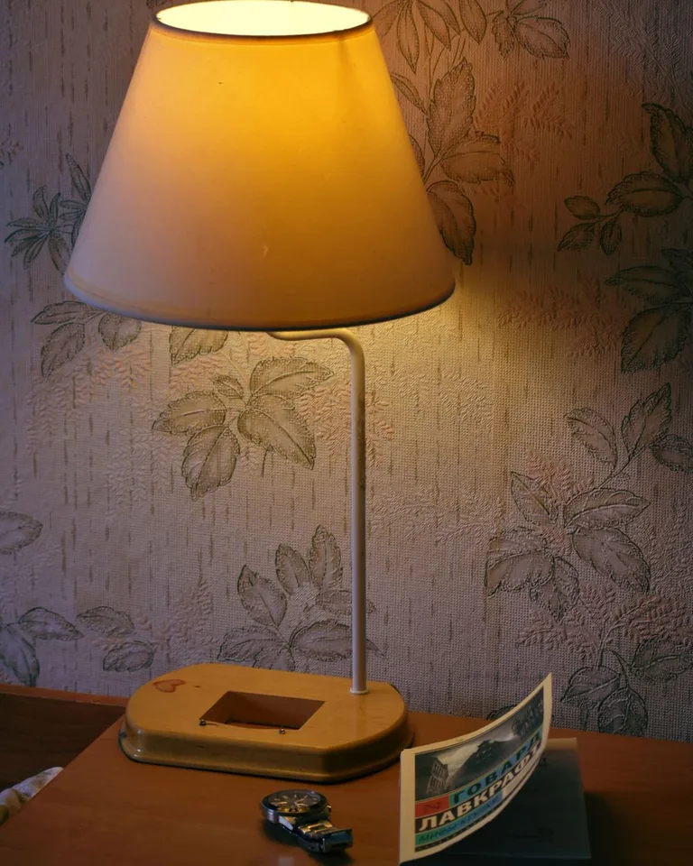 A warm bedside lamp glowing on a nightstand beside a book and a watch