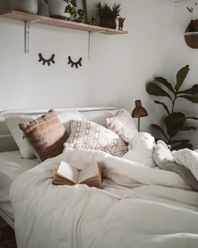 Bedroom corner with potted plants on a wall shelf and a large leafy plant beside the bed