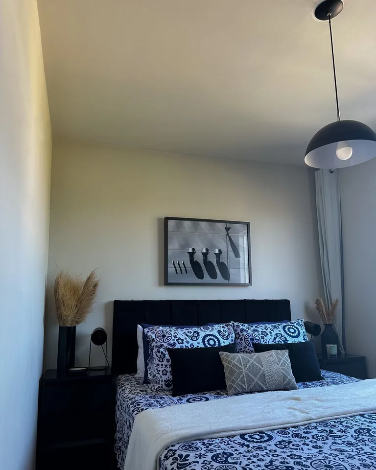 Framed black-and-white artwork hanging above a bed with patterned blue bedding