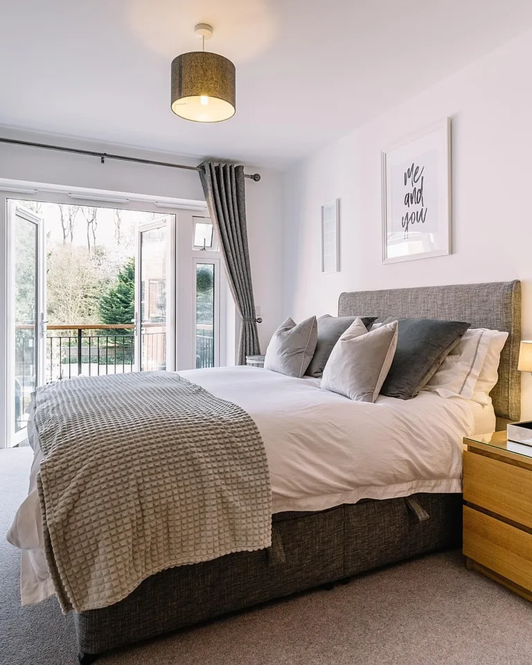 Bright small bedroom with a bed, desk area, and shelves