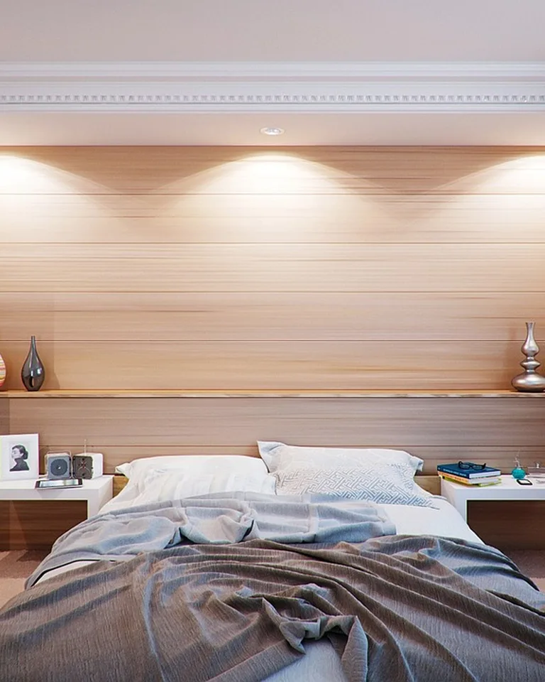 Wood-paneled headboard wall with shelves holding books and decor above a bed
