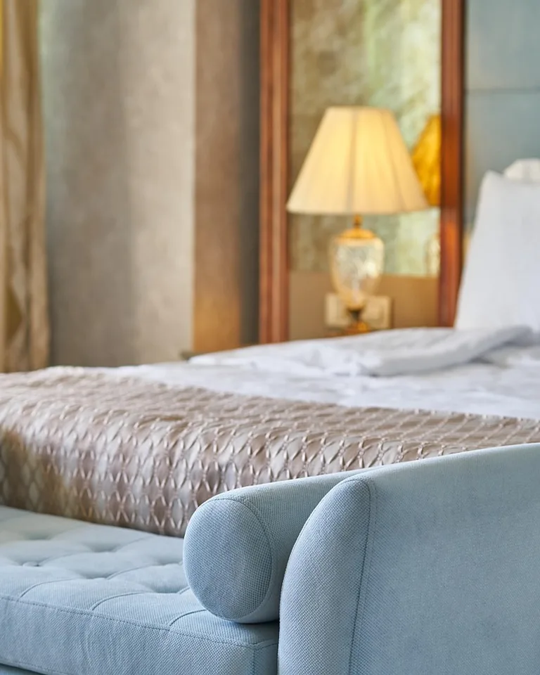 Upholstered storage bench at the foot of a bed with a cushioned seat