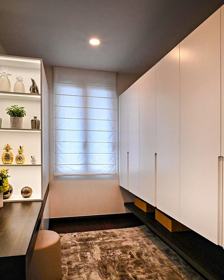 Bedroom wall with built-in wardrobes and lit shelves beside a window