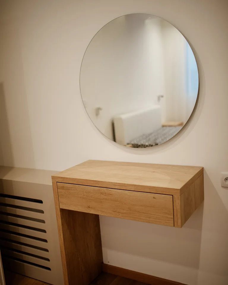 Round mirror above a modern wooden vanity