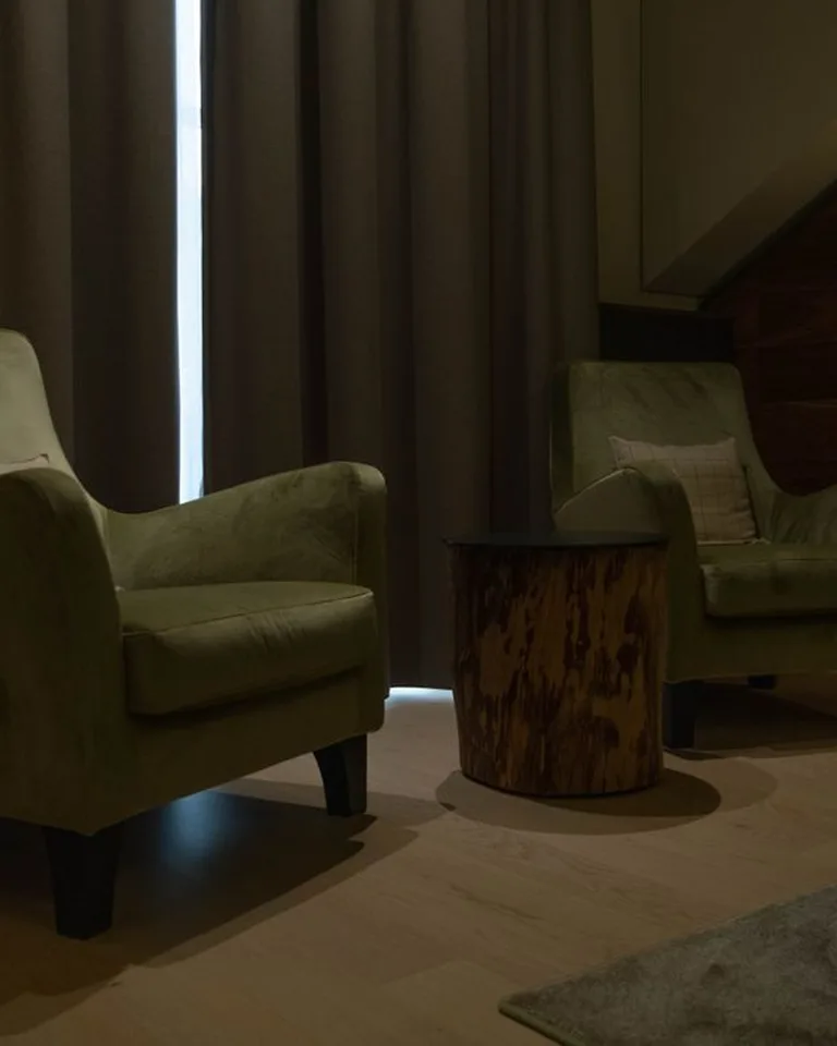 Rounded green upholstered accent chairs in a bedroom seating area with a sloped wall