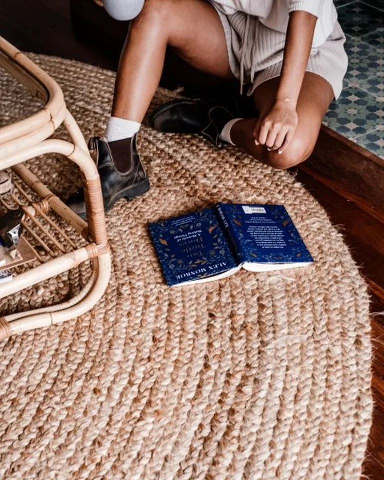 Round woven jute rug on a wooden floor with a book resting on it