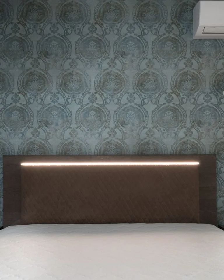 Pair of small wall sconces mounted above a bed headboard