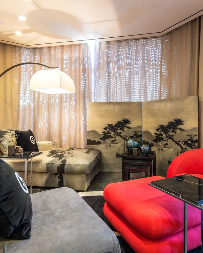Sculptural arc floor lamp with a dome shade curving over a bedroom reading chair
