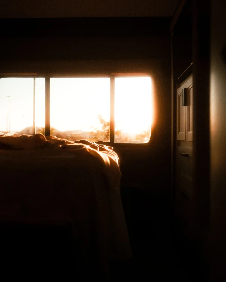 A moody bedroom at dusk with warm light streaming through the window