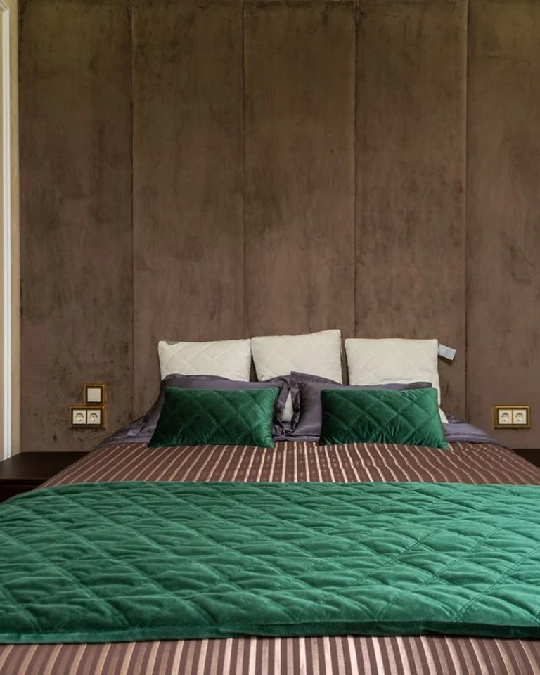 A cozy bedroom with the bed tucked into a corner against a wood-paneled wall