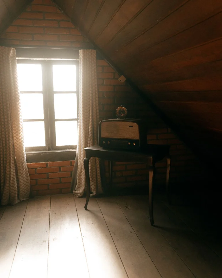 An attic bedroom with a sloped wooden ceiling, a window seat, and warm natural light
