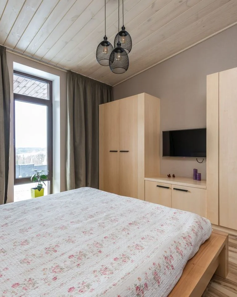 A bedroom with a full wall of light wood wardrobes and sliding closet doors