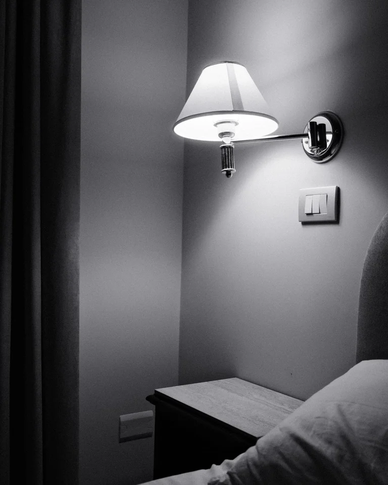 A wall-mounted sconce and dark painted bedroom wall with matching trim
