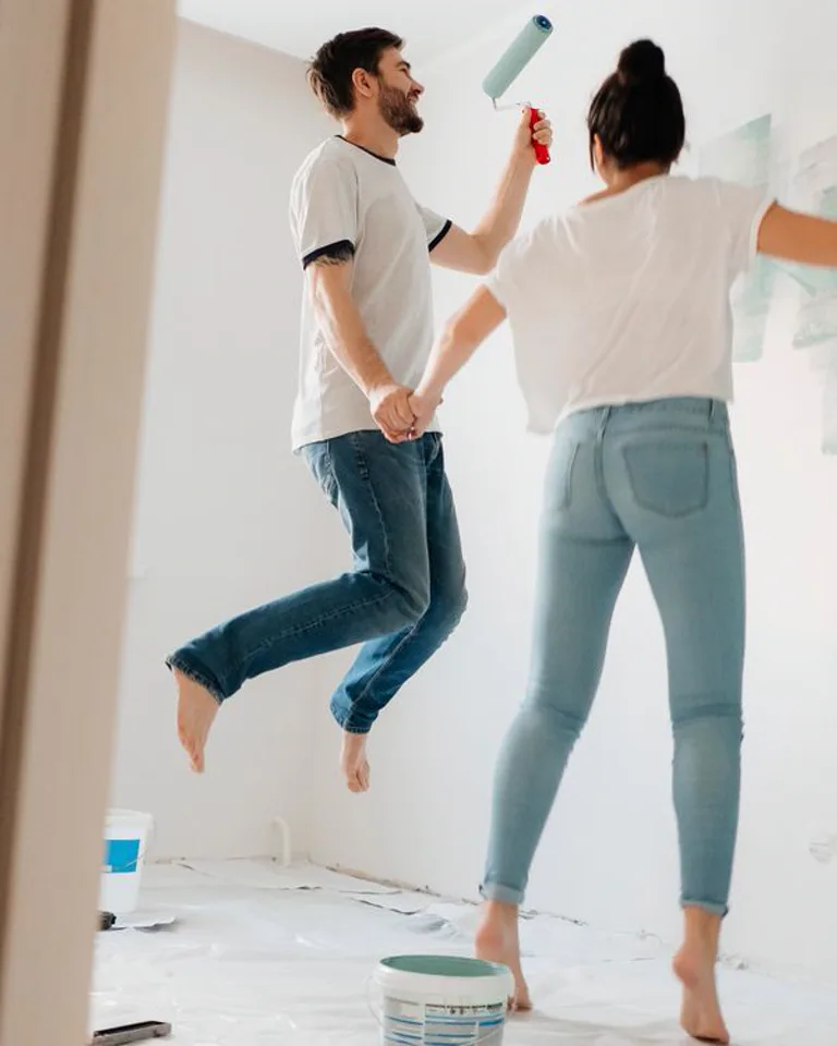 Couple painting a bedroom wall during a makeover