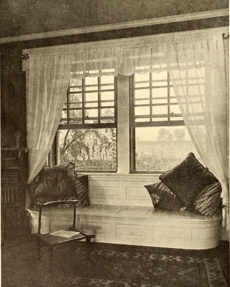 Built-in window seat with cushions under bedroom windows