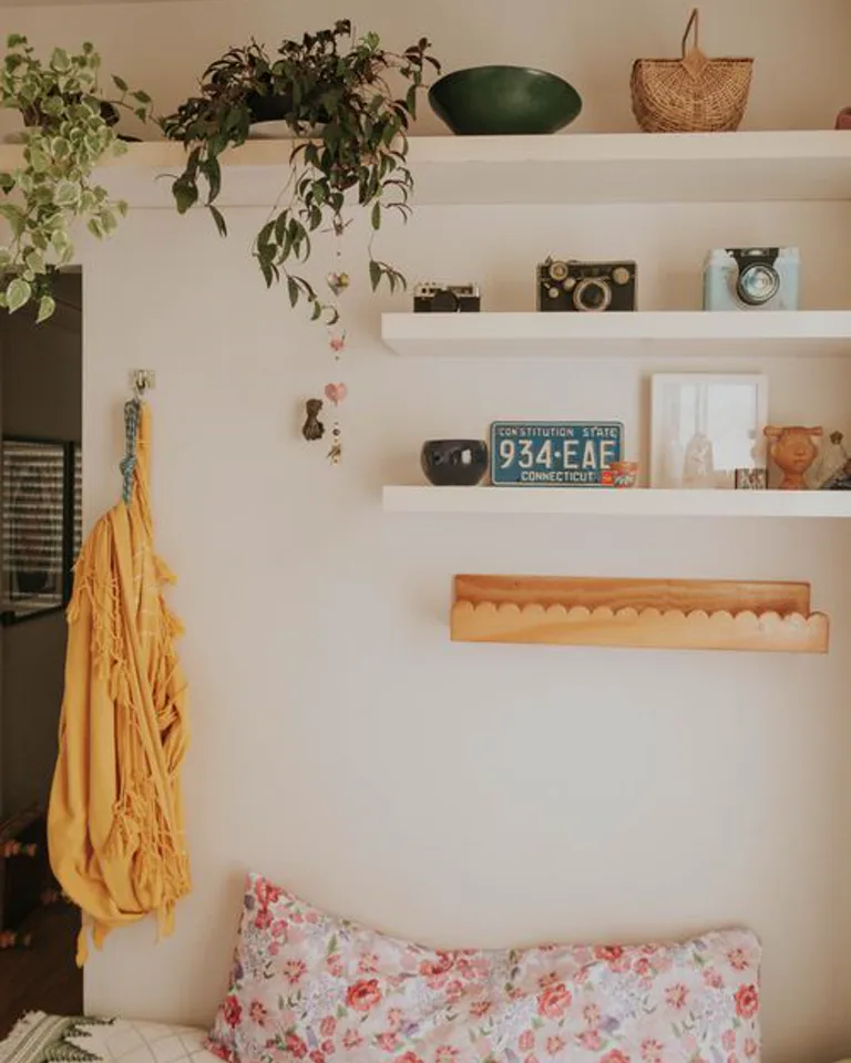 Bedroom wall shelves holding books, plants and decorative storage