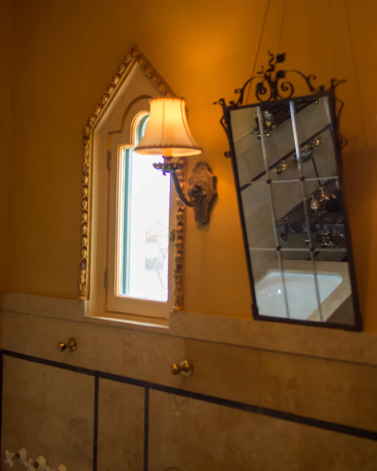Ornate bathroom mirror flanked by warm wall sconces on both sides