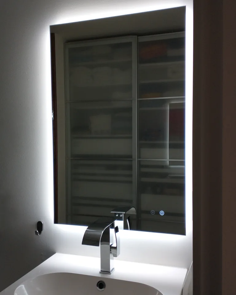 Close-up of a backlit LED bathroom mirror with glowing edges