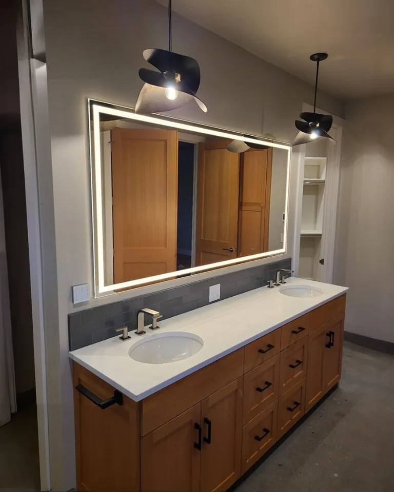 Double vanity with pendant lights hanging beside illuminated mirrors