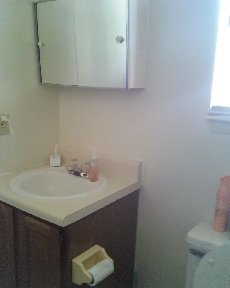 Compact bathroom vanity with mirror in a simple rental-style bathroom