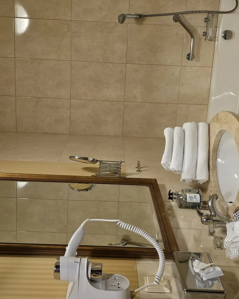 Hotel bathroom vanity area with layered ceiling and mirror lighting