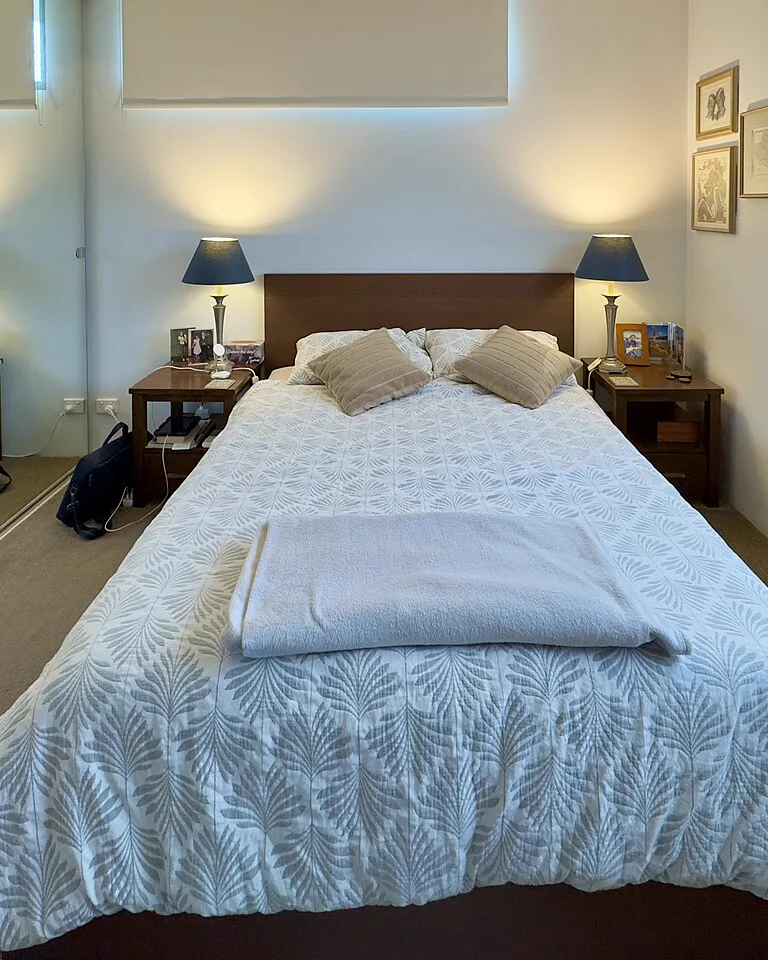 Bed tucked into one leg of an L-shaped bedroom layout