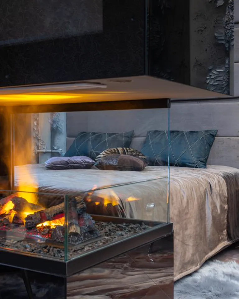 Bed on the wall opposite a bedroom fireplace with clear space around the hearth