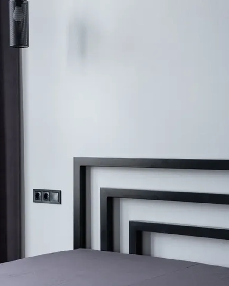 Black geometric headboard against a white bedroom wall