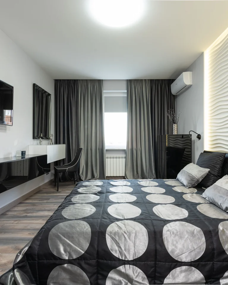 Black and white bedroom with layered bedding and contrasting furniture