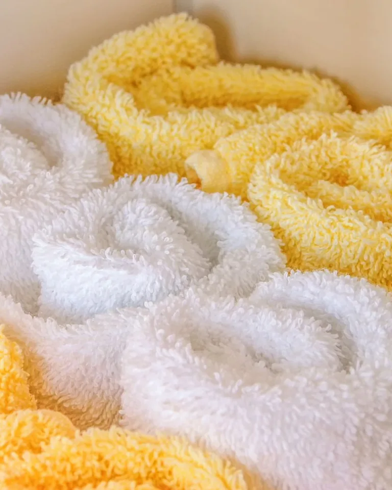 Neatly rolled white and cream towels in a bathroom