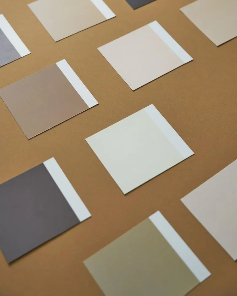 Warm beige paint color swatches held against a bedroom wall