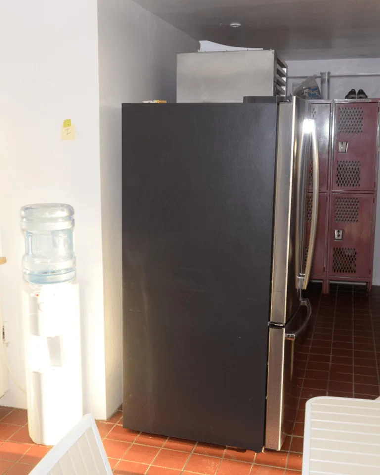 A white kitchen with refreshed cabinets, black refrigerator, and updated lighting after a budget remodel