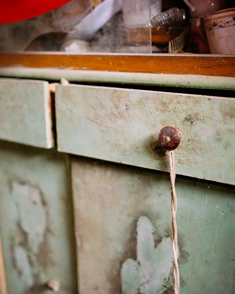Close-up of a vintage green cabinet with a wooden knob