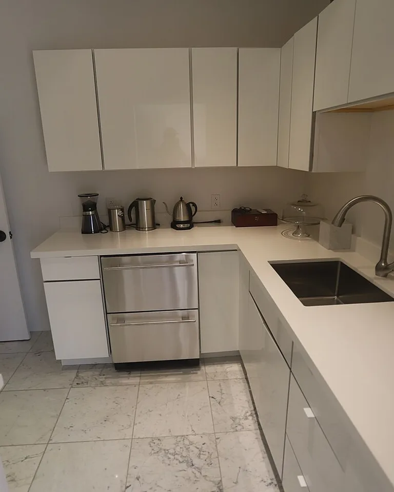 White kitchen cabinets with light countertops and marble-look flooring