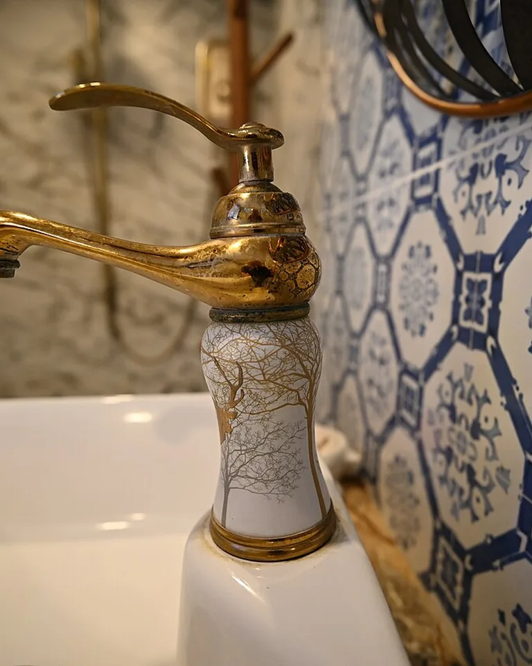 Ornate gold-toned faucet with natural patina beside a white sink