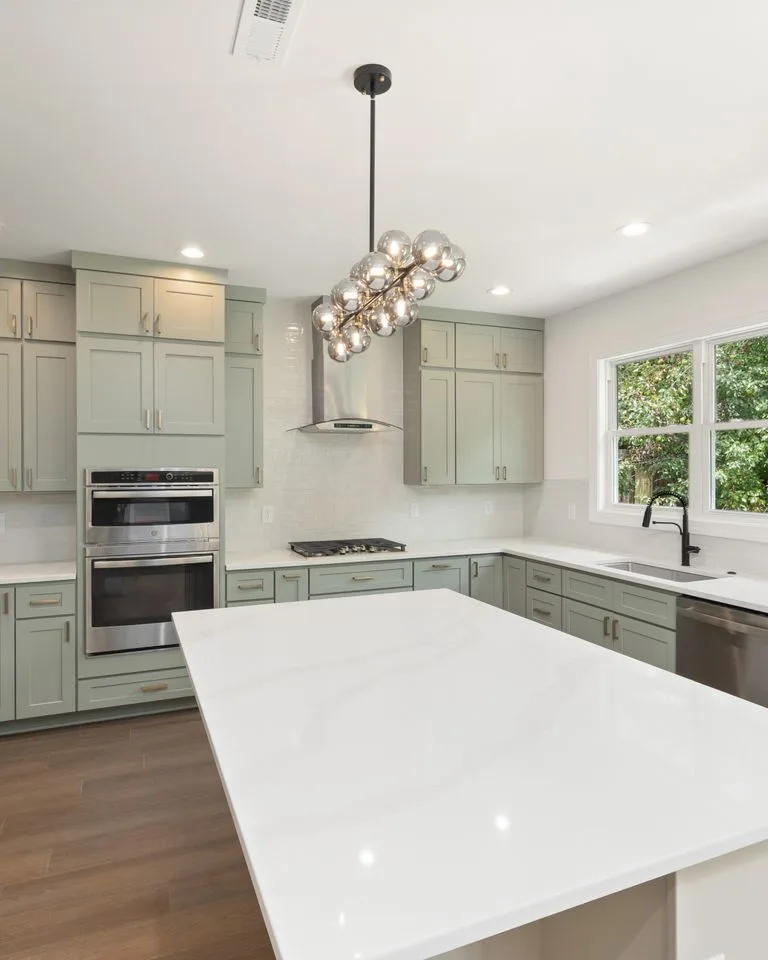 Sage green kitchen cabinets in a bright kitchen interior