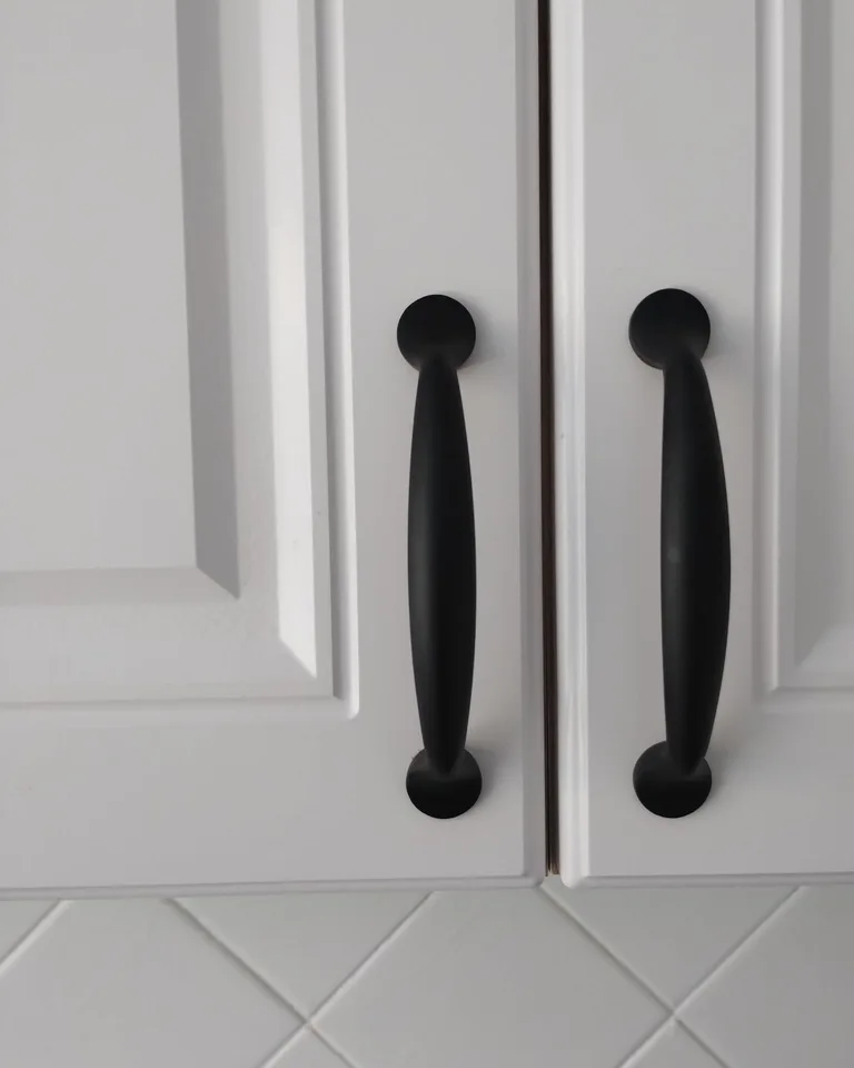 Close-up of modern black cabinet handles on kitchen cabinetry