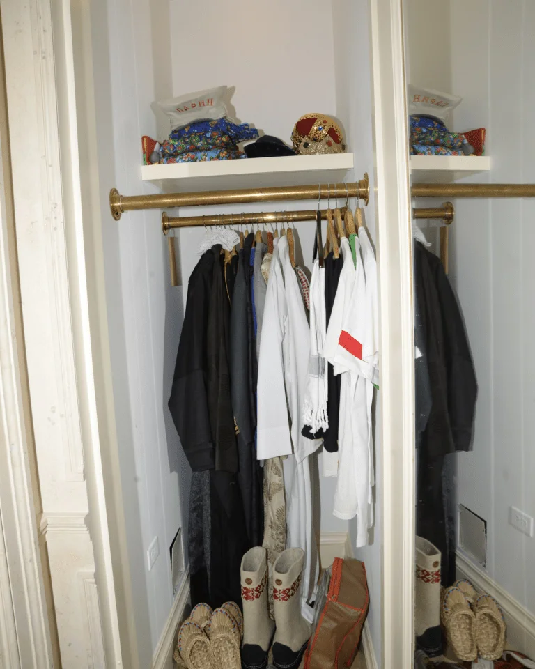 A small closet crowded with clothes and shoes, showing a storage space that was never edited