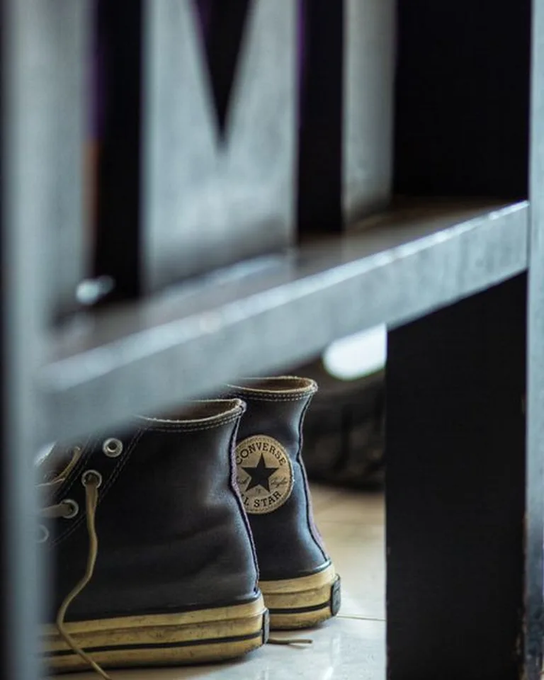 Sneakers tucked under a bench at the door, kept in their daily spot