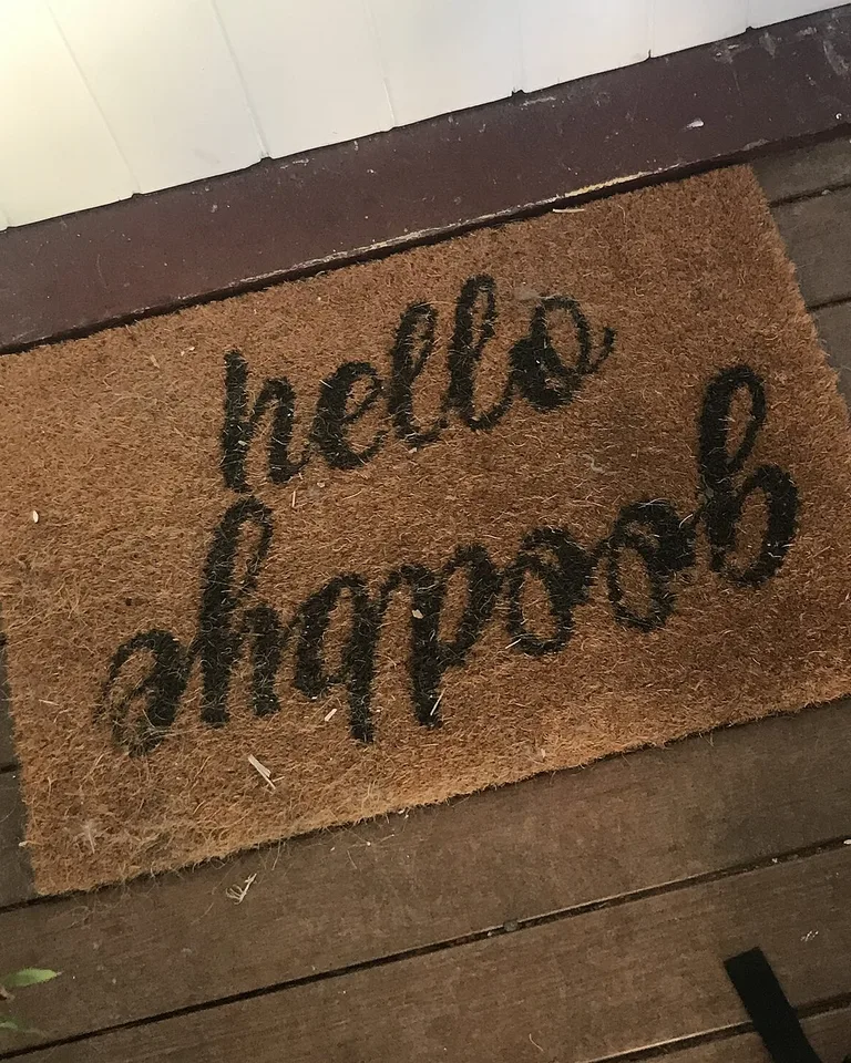 Coir welcome mat with a hand-lettered hello message at a front door
