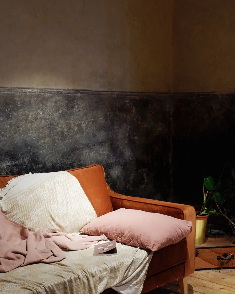 Rust-toned sofa layered with throw pillows and a blanket