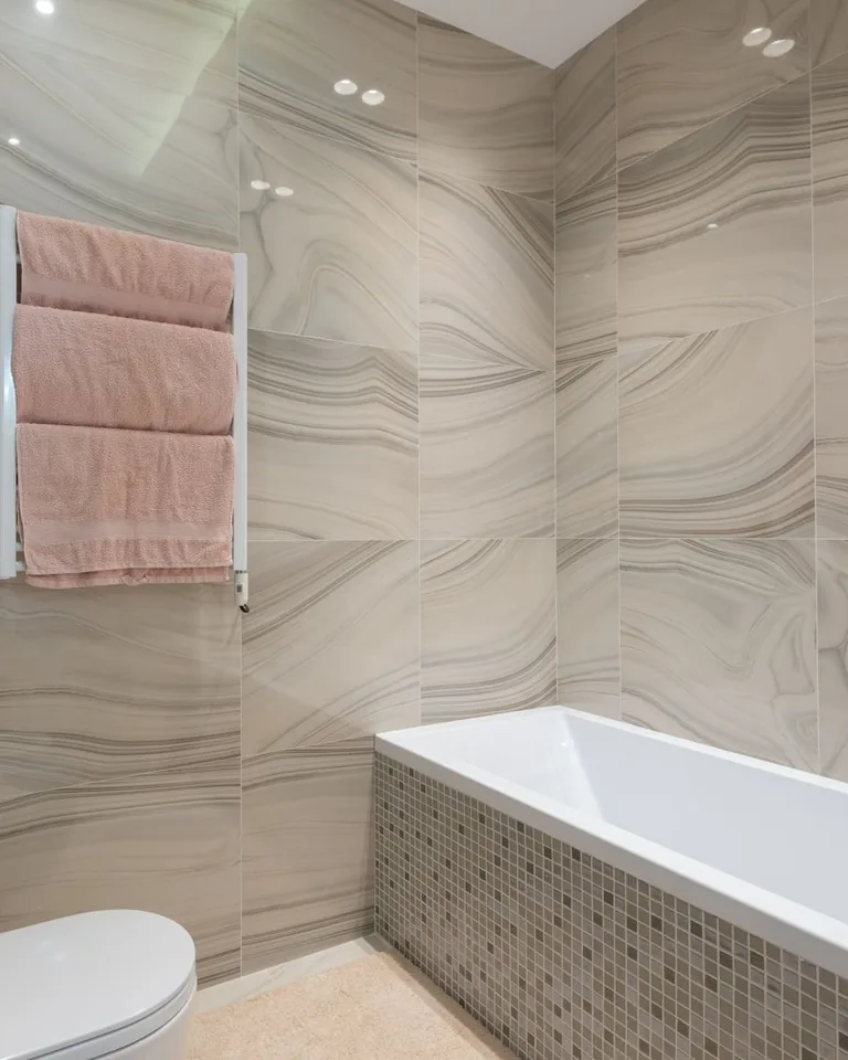 Beige bathroom with marble-look tile walls and a modern freestanding bathtub