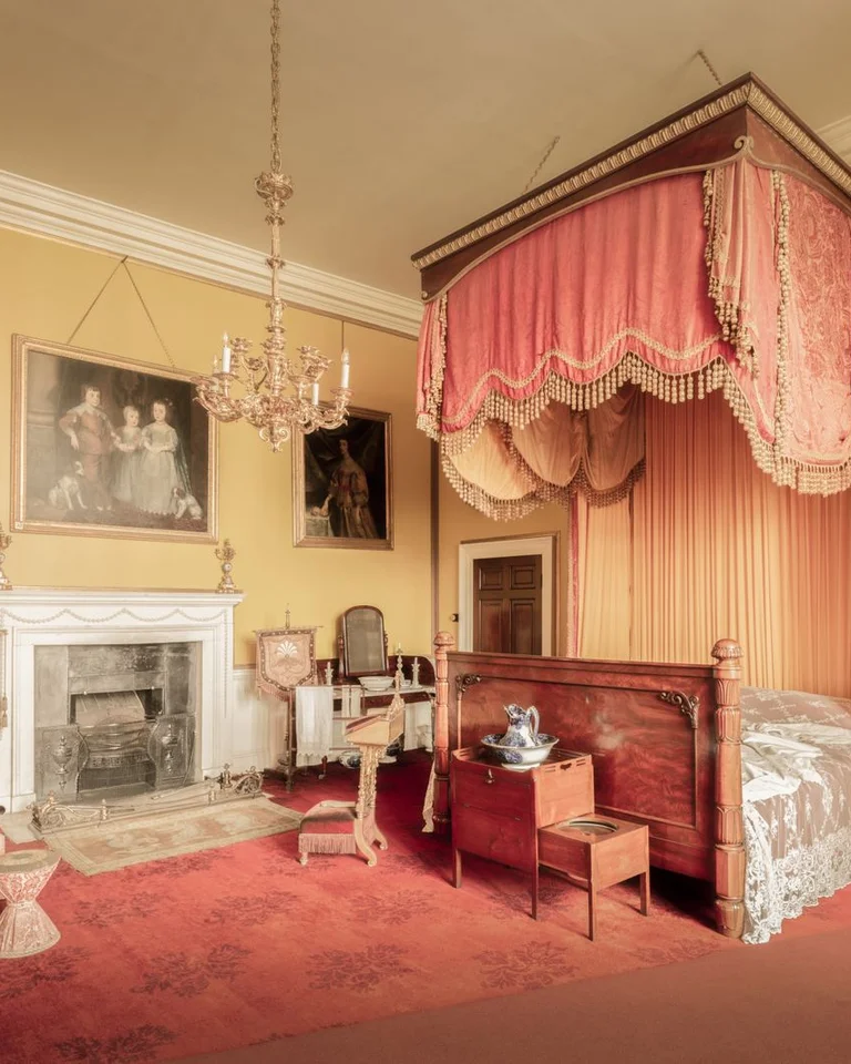 Elegant traditional bedroom with a canopy bed, fireplace, and classic furnishings