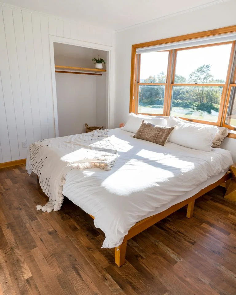 Modern farmhouse bedroom with white bedding and a natural wood bed frame