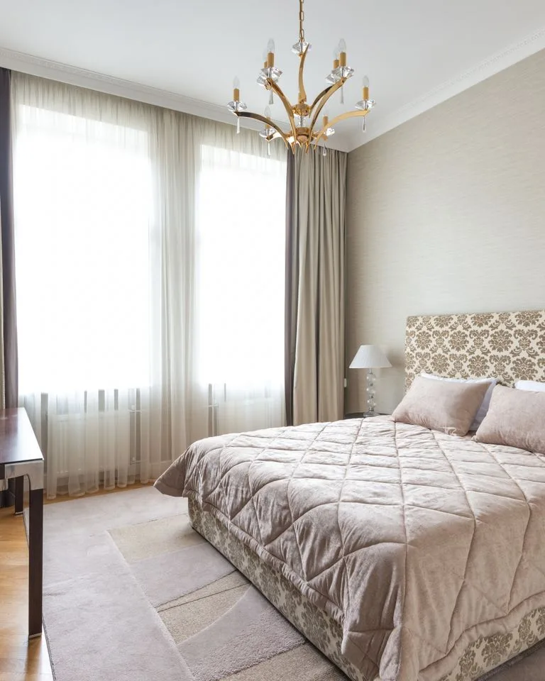 Warm beige bedroom with layered neutral bedding and soft natural light