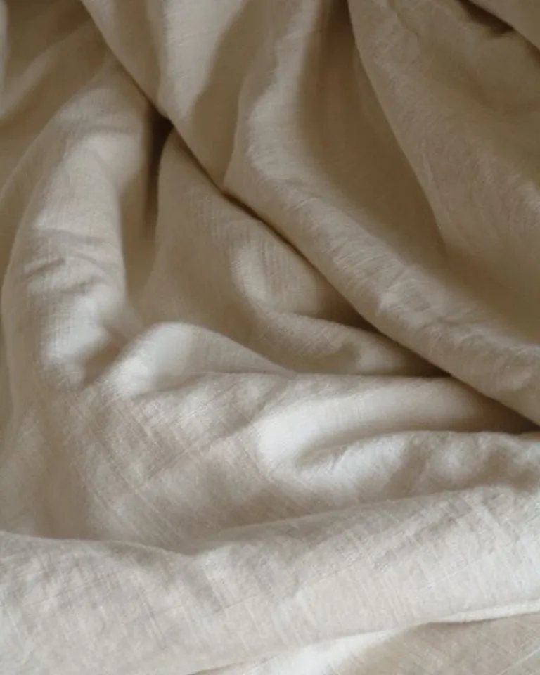 Rumpled white linen bedding on an elegant bed