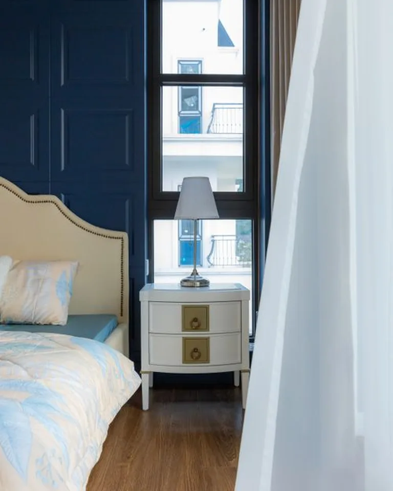 Hand-painted vintage nightstand in creamy white beside a bed