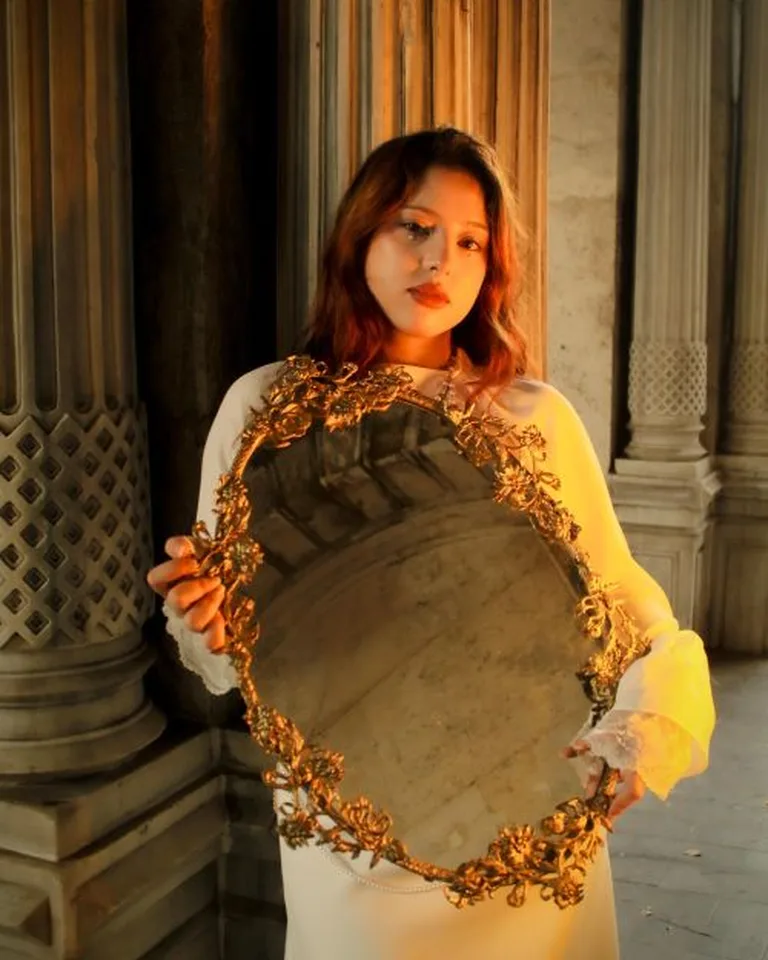 Ornate vintage gold mirror hung above a bedroom dresser