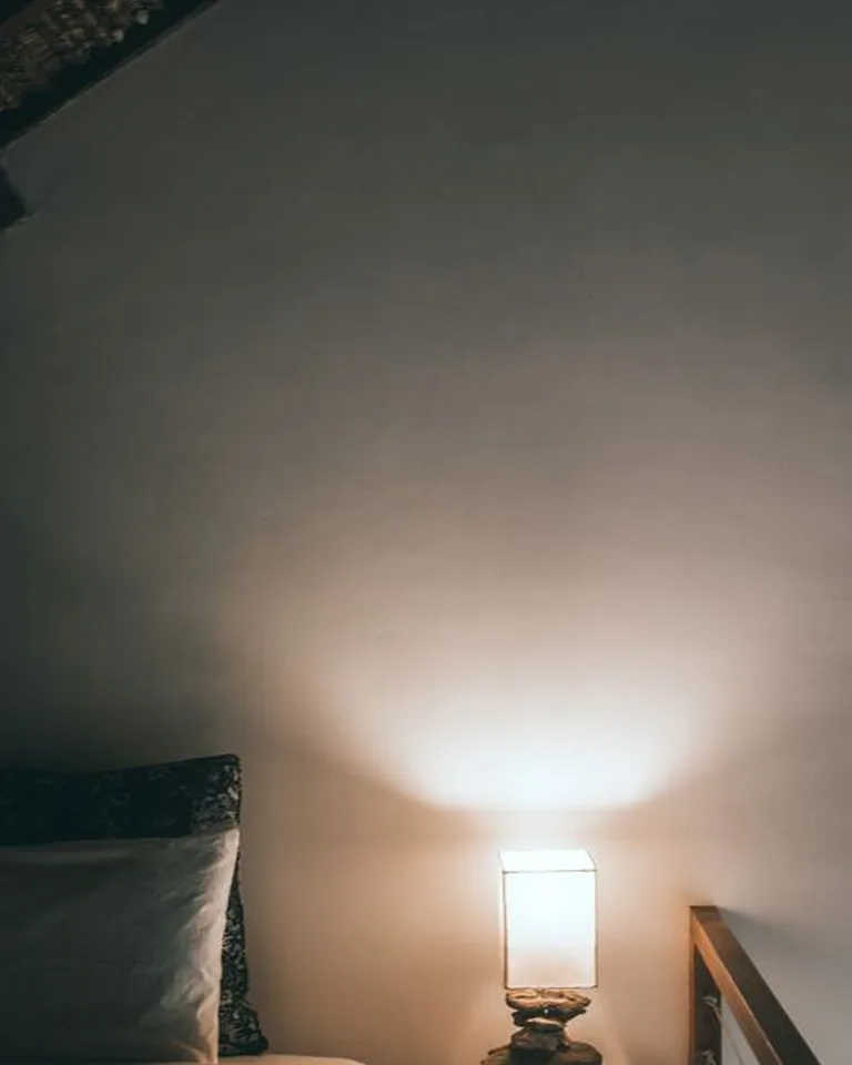 Antique-style table lamp glowing on a bedroom nightstand