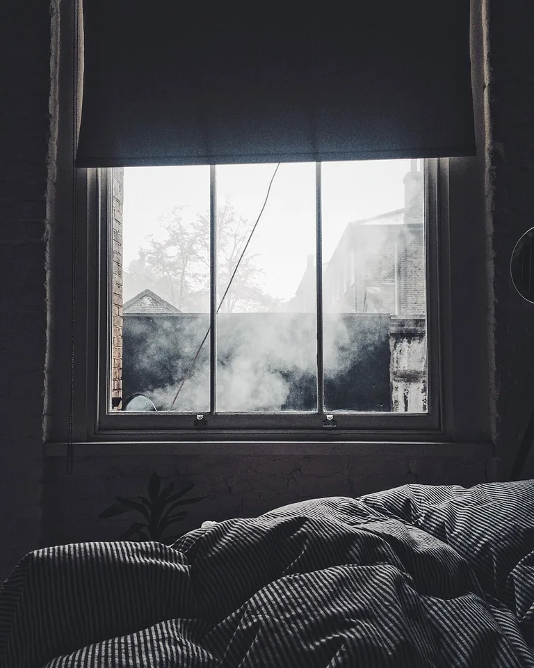 Daylight streaming through a bedroom window opposite a full-length mirror